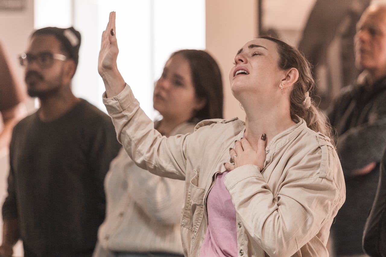 A group of diverse individuals engaging in a spiritual prayer service indoors. Emotional expressions are evident.