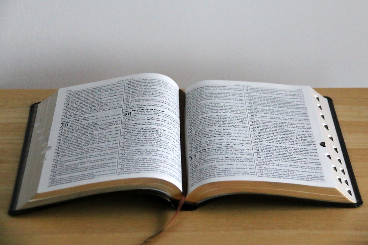 A close-up view of an open Bible on a wooden table, showcasing detailed text.